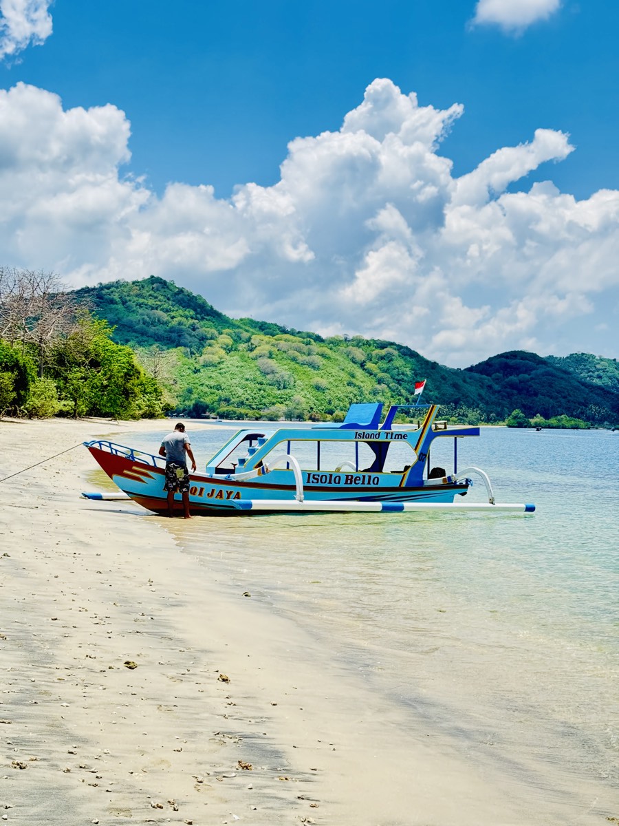 A painted outrigger boat moored off a shallow beach