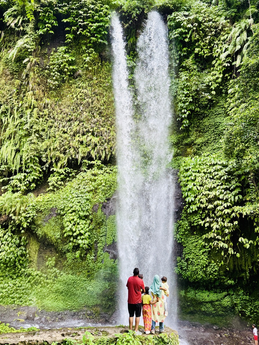 The family small at the foot of a jungle waterfall